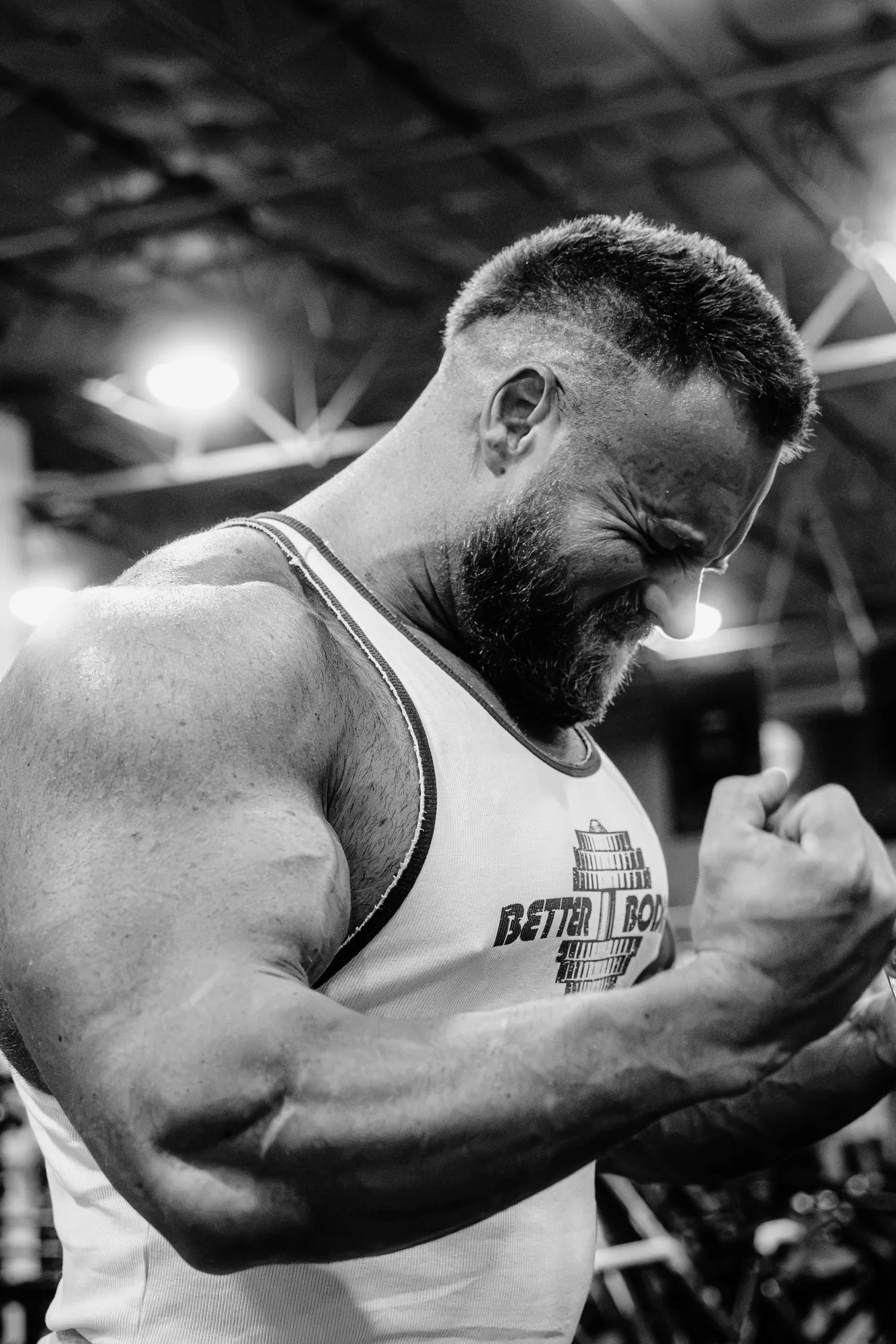 Carl Bruce mid-set at a cable machine, head down, lit hard from above.
